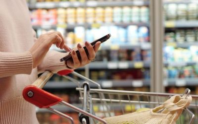 Side view close up of woman shopping in supermarket and using smartphone, copy space